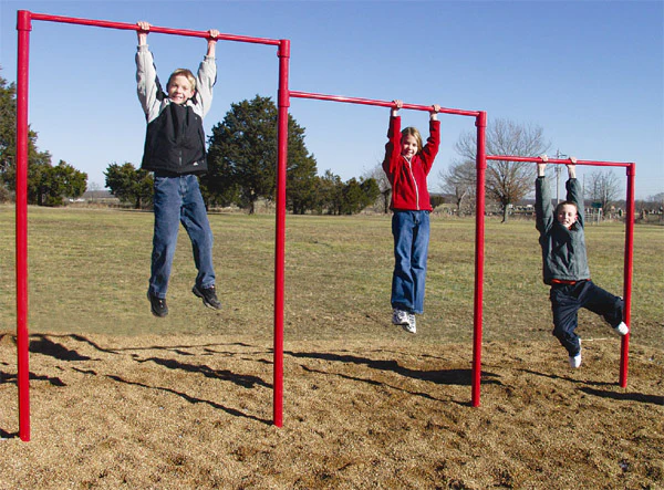 Three young people hanging from red monkey bars on playground